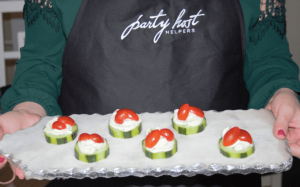 party host helper holding cucumber tomato bites tray